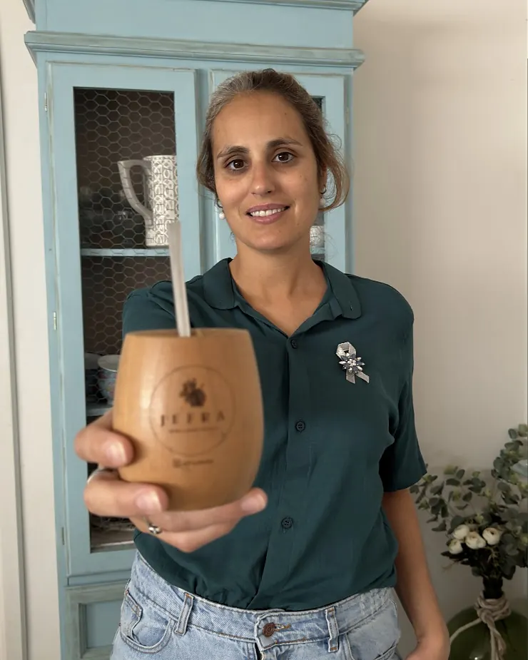 Yesi, de Jefra, sosteniendo un mate de madera con el logo de la marca.
